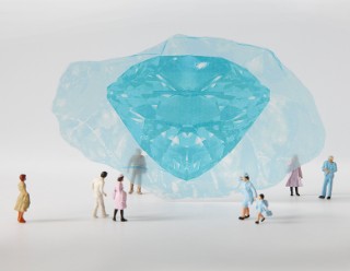 Kleine Figuren stehen vor einem blauen Edelstein.