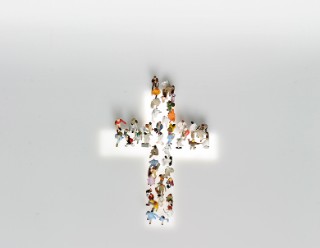 Kleine Figuren auf einem Kreuz aus Licht.