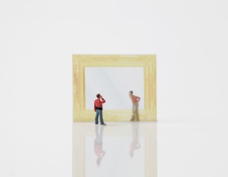 Kleine Figuren stehen vor einemgoldenen Rahmen.